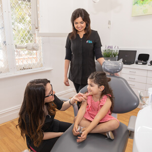 Dr Hobeika and assistant with little girl in dental chair